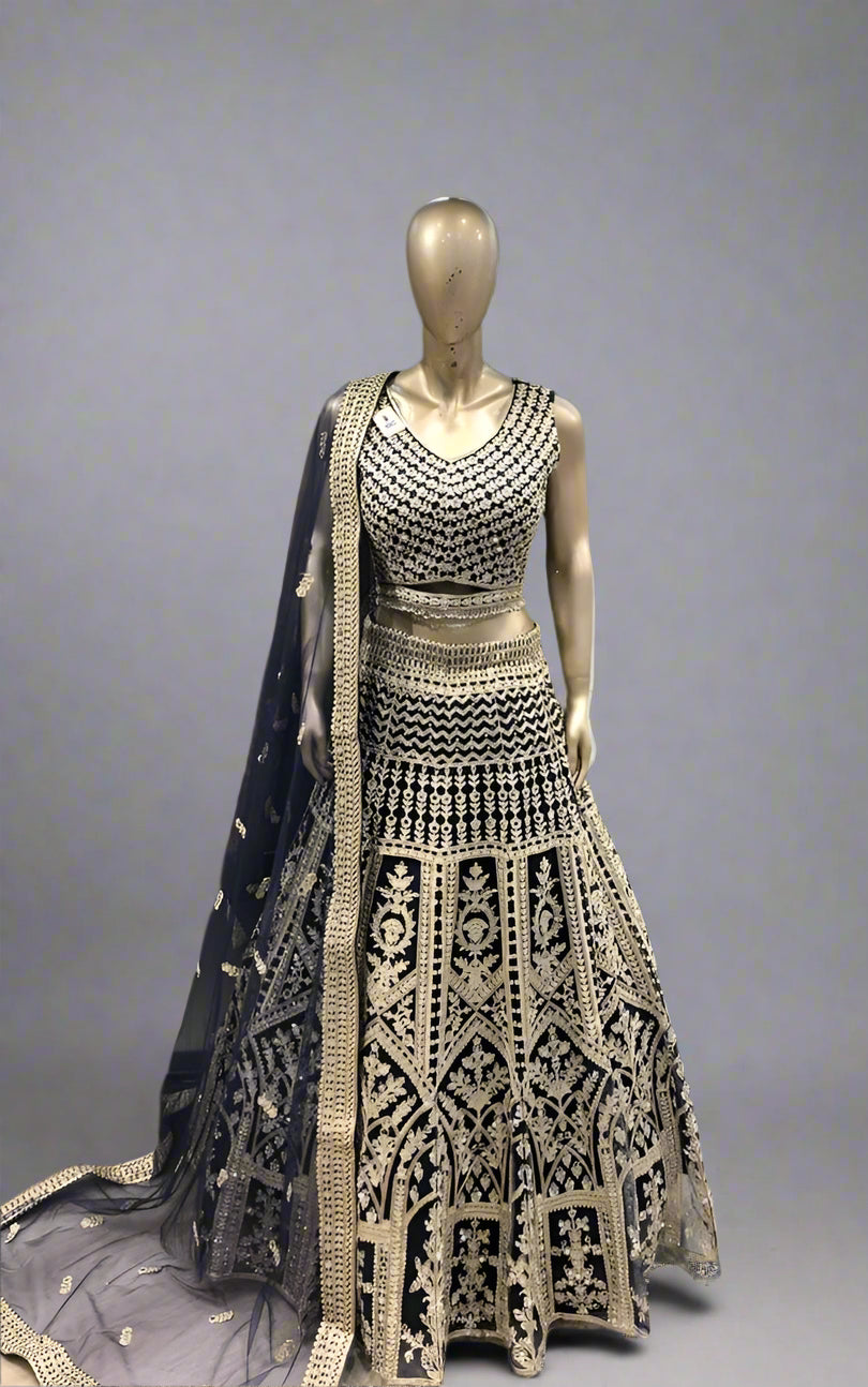 Elegant black and gold embroidered traditional outfit on a mannequin against a colorful fabric background.